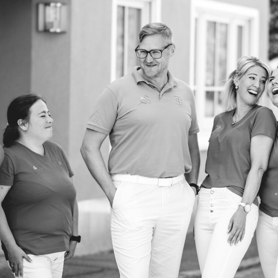 Praxisteam draußen vor der Praxis in Grautönen